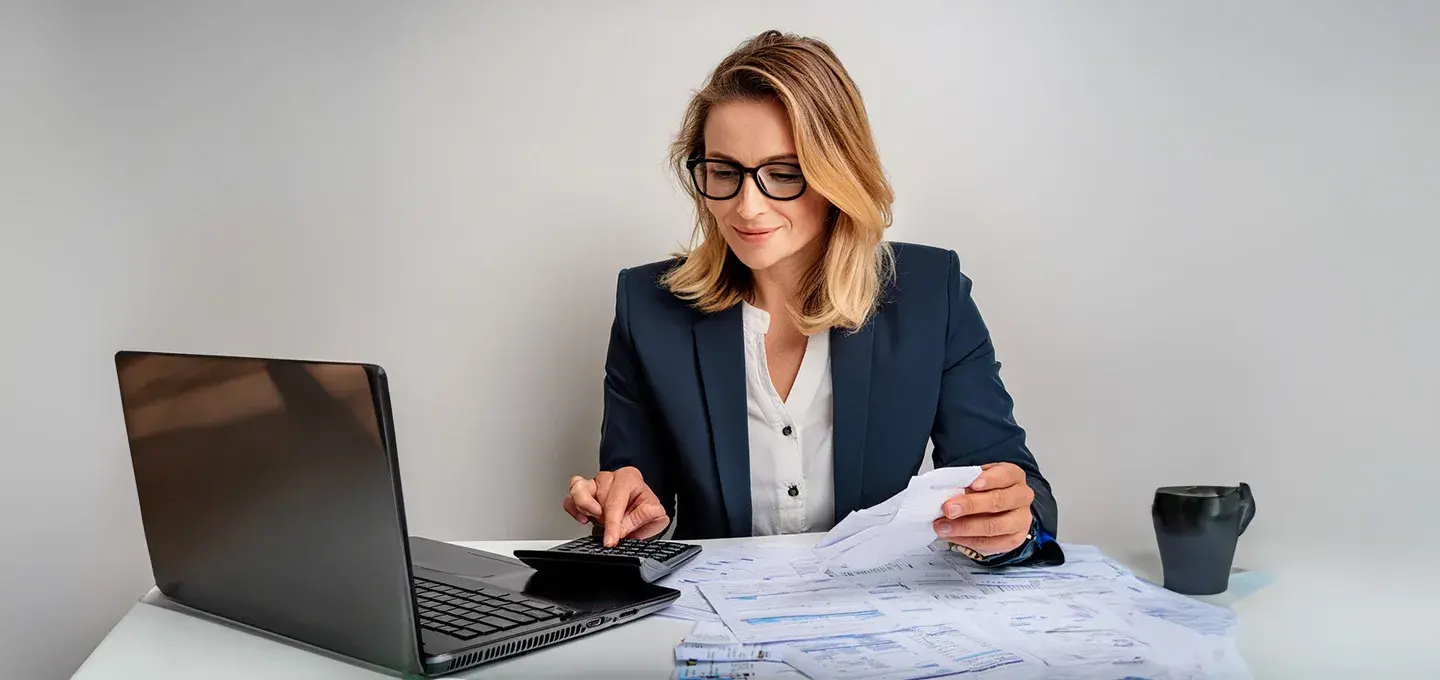 A woman sitting at a desk with a computer and papers