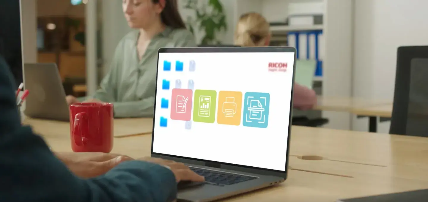 A person sitting at a table with a computer and phone